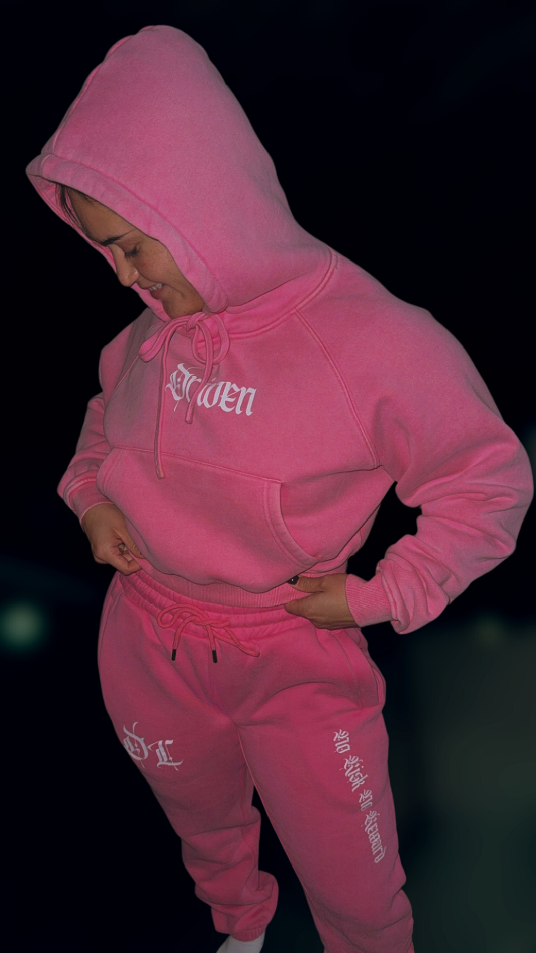 Person wearing a pink hoodie and pants with text on a dark background