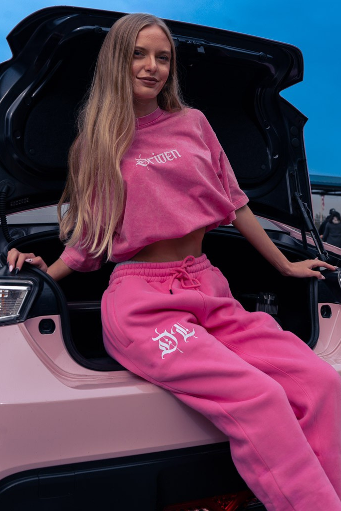 Person wearing pink outfit with visible branding sitting inside a vehicle.