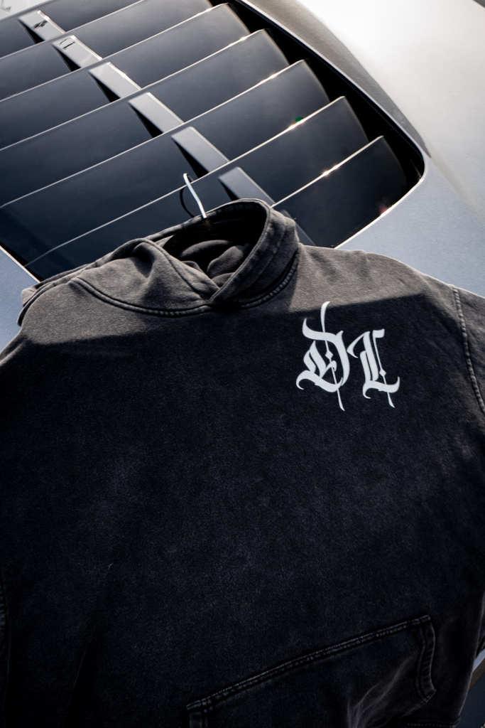 Black snow washed jacket with a white logo on a car's air vent background