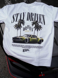 White t-shirt with car graphic and 'Stay Driven' text on a vehicle's rear window.
