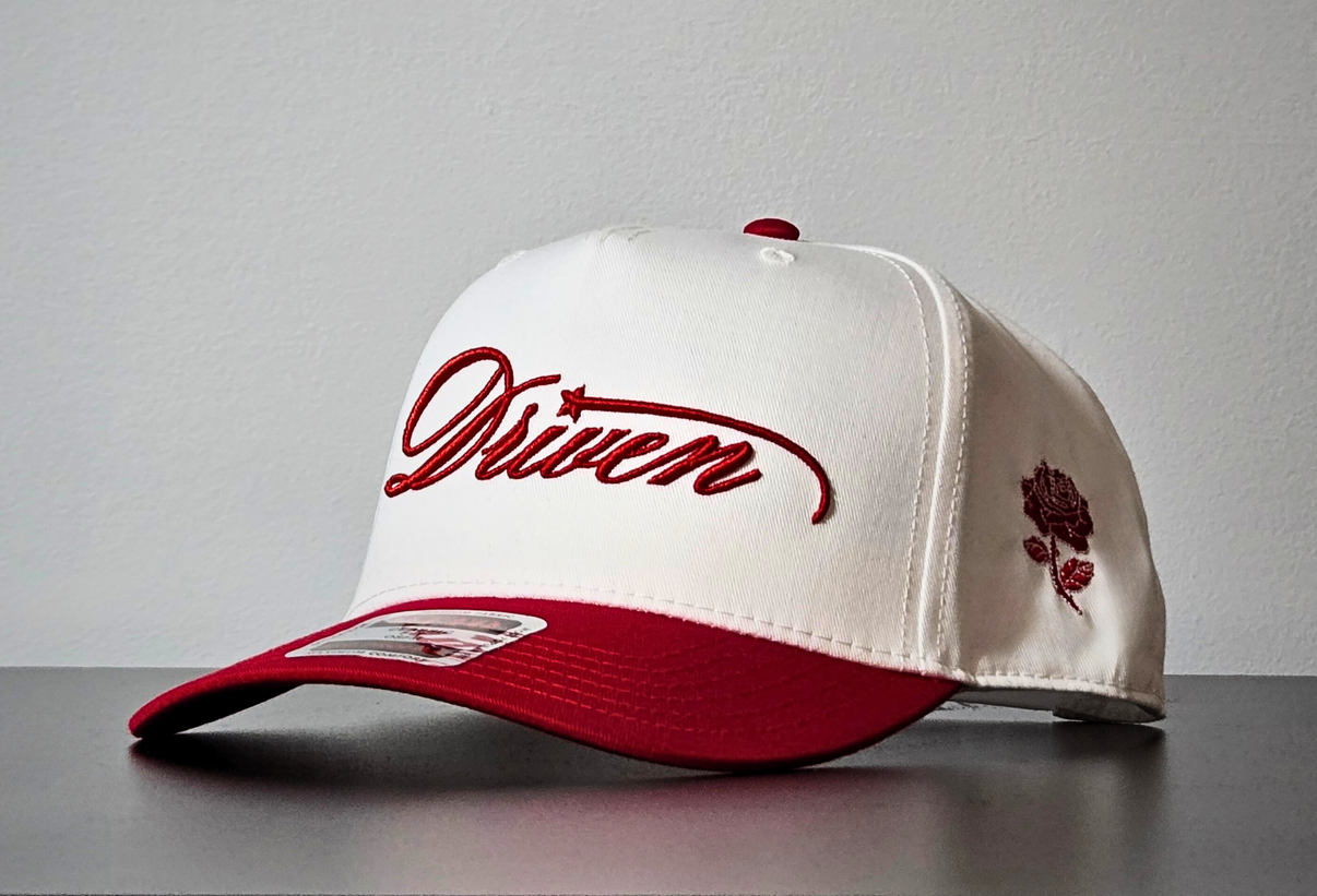 White and red cap with 'Driven' logo on a gray surface