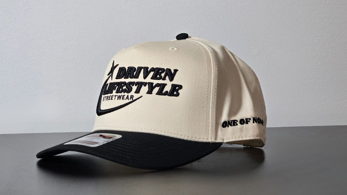 Beige and black cap with branding on a gray surface and background