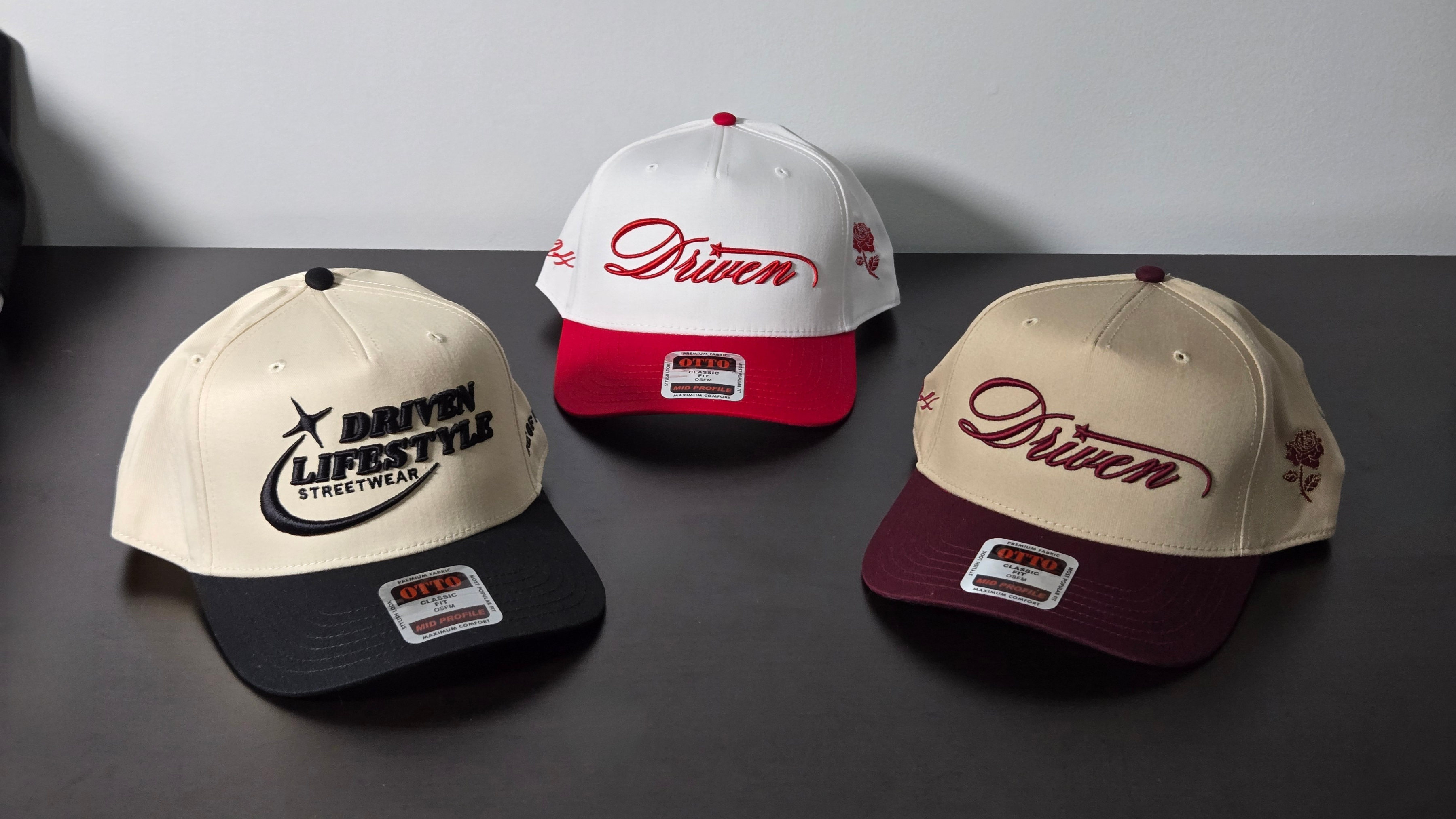 Three caps with 'Driven' branding on a dark surface