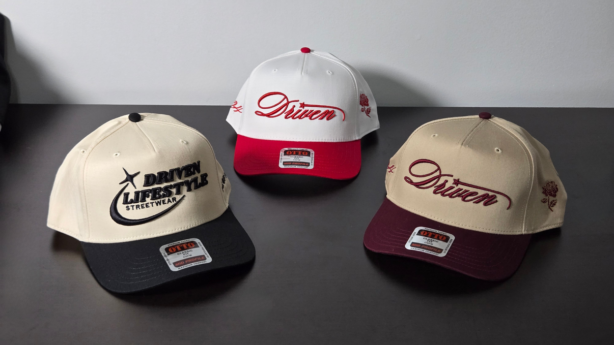 Three caps with 'Driven' branding on a dark surface