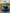 Blue sports car with open hood on a road during sunset