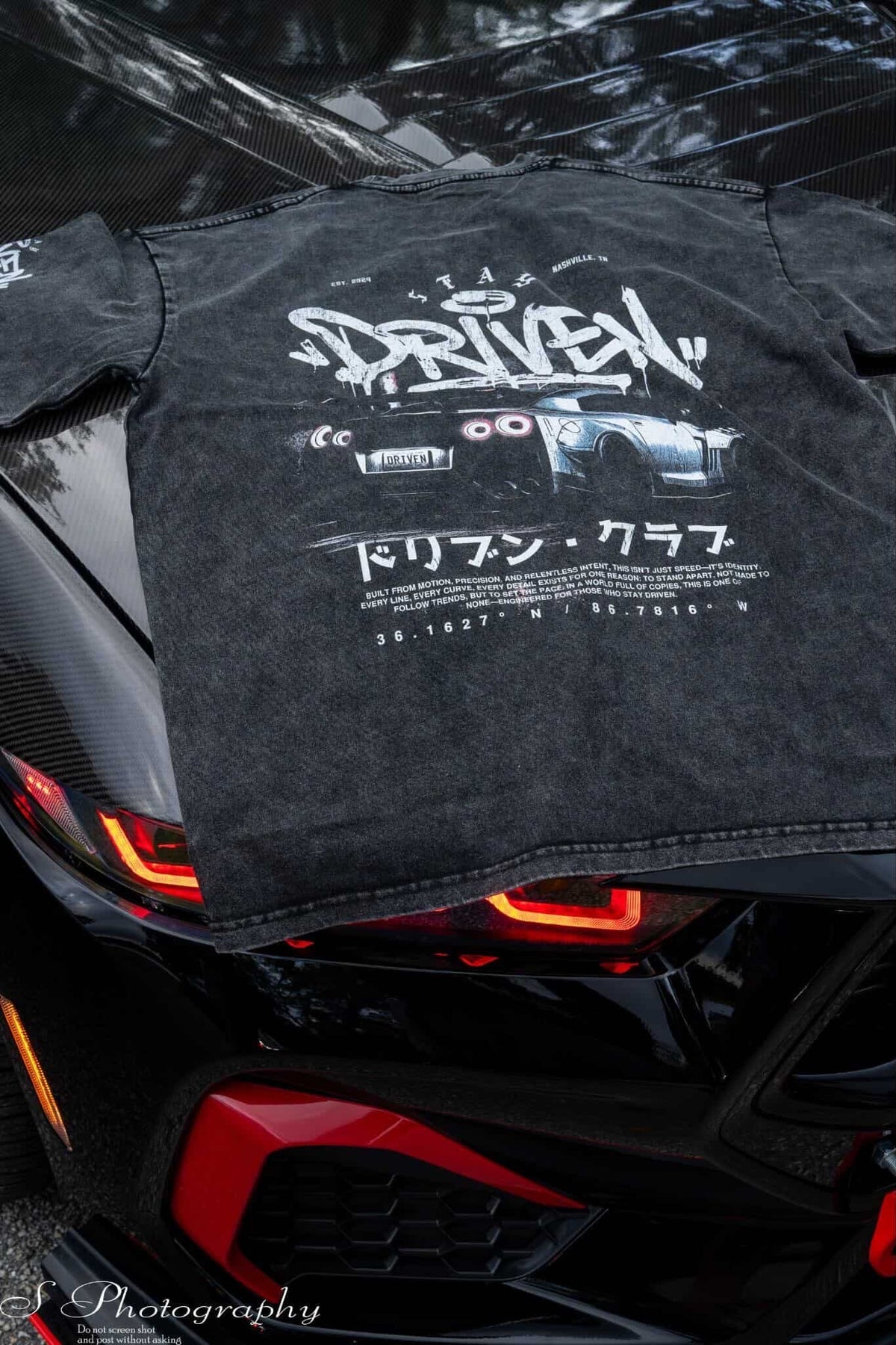 Black t-shirt with white text and graphics on a black car
