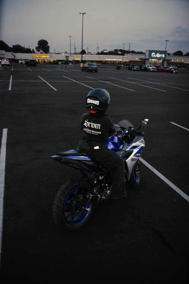 Person on a motorcycle in a parking lot with a building in the background