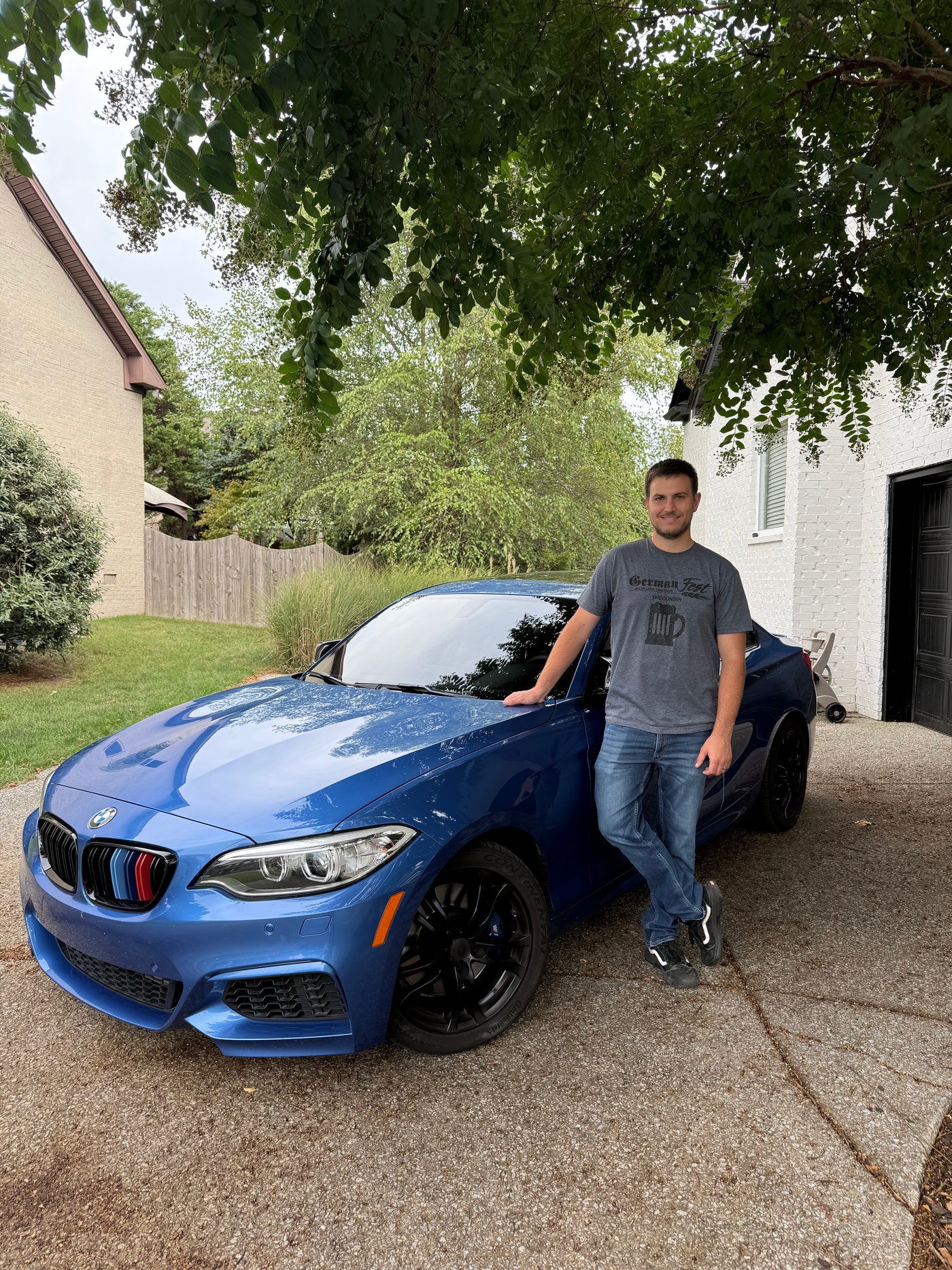 blue bmw and man standing next to it outside