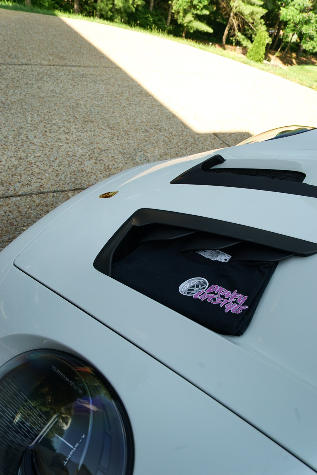 Car hood with a black decal featuring a logo and text on a road.